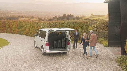 A driver ready to pick up passengers outside a house, as part of our return UK travel service